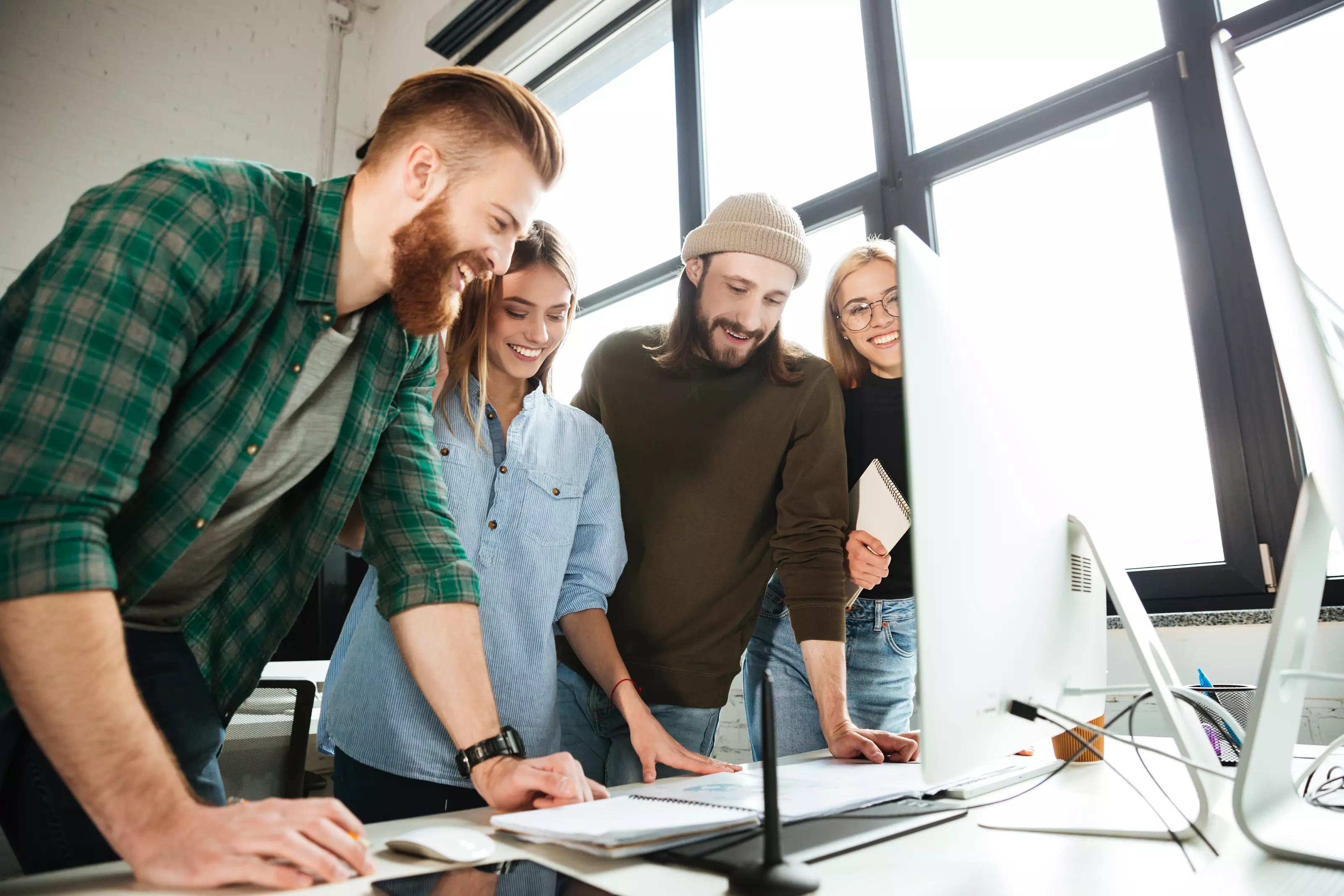 happy-colleagues-standing-office-using-computer_43